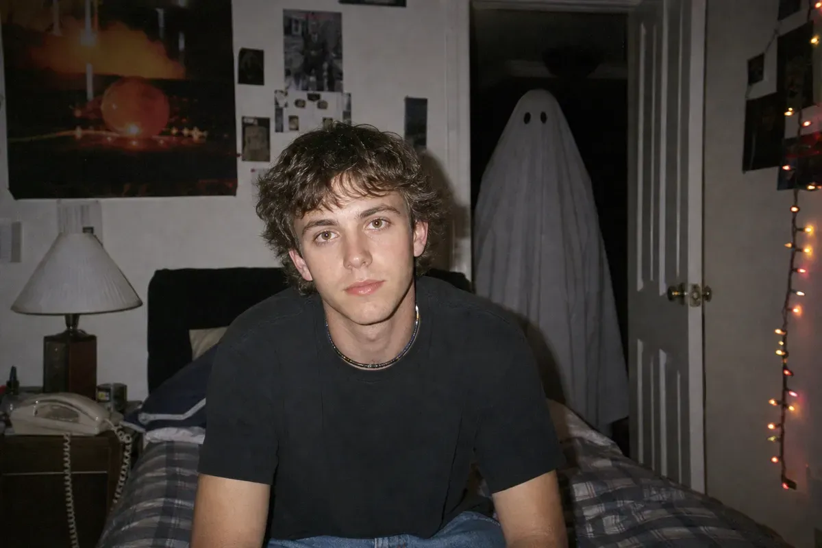 Y2K-style flash portrait in a 90s bedroom with a bedsheet ghost standing in the dark doorway